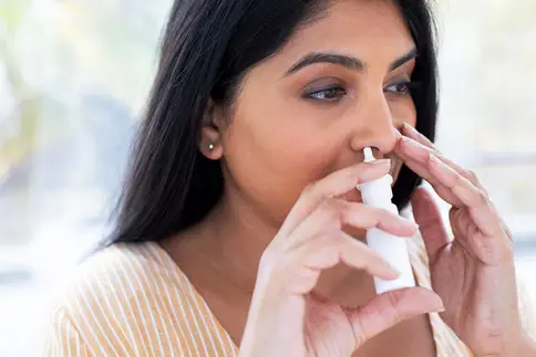 photo of woman using nasal spray